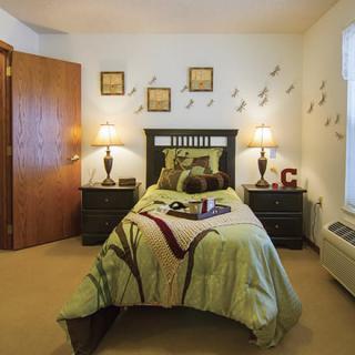 A cozy bedroom with a single bed, wall art, and warm lighting from bedside lamps.