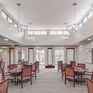 A modern and spacious dining area with neatly arranged tables and chairs, featuring stylish lighting.