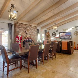 A cozy dining and living area with a brick fireplace, vaulted ceilings with wooden beams, and modern furnishings.