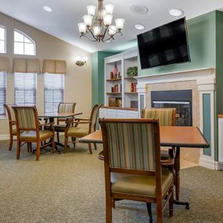 A cozy living room with tables, chairs, a fireplace, and a television.