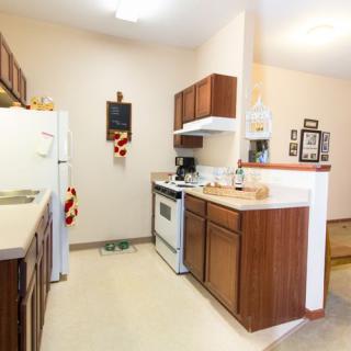 A cozy kitchen with wooden cabinets, a refrigerator, and a stove.