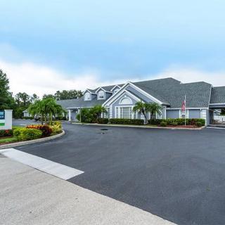 A suburban building with a landscaped parking area and a clear sky.