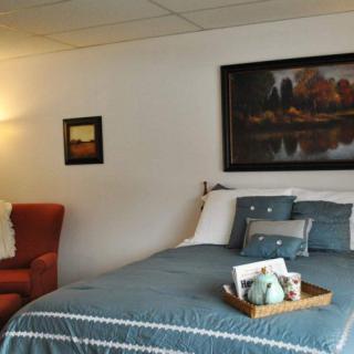 A cozy bedroom with blue bedding, decorative pillows, and wall artwork.