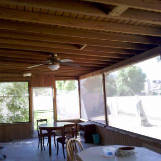 A cozy screened-in porch with a dining area and ceiling fan.