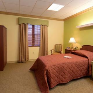 A cozy bedroom featuring a single bed, bedside lamp, and warm decor.