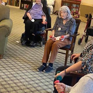 A group of seniors participating in a seated exercise session indoors.