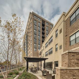 A view of a modern apartment building with an outdoor seating area and overcast sky.