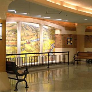 A well-lit indoor space featuring benches, a mural, and decorative railings.