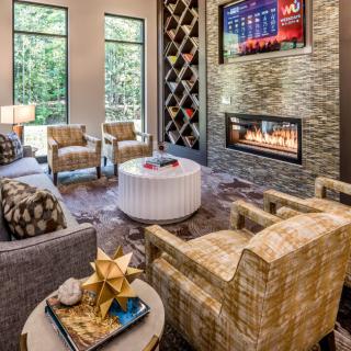A contemporary living room featuring a cozy seating area with a fireplace and a wall-mounted television, enhanced by modern decor and large windows.