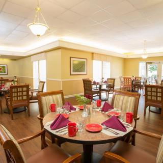 A warmly-lit dining room with round tables elegantly set for a meal.