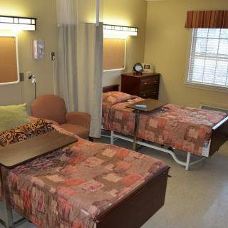A hospital room with two beds, separated by a curtain, and equipped for patient care.