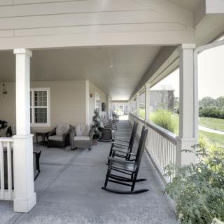 A spacious covered porch with rocking chairs and outdoor seating, offering a relaxing view.