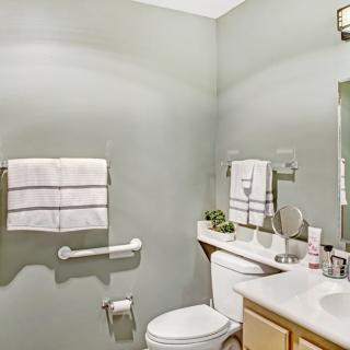A clean and simple bathroom with light-colored walls, a toilet, a sink, and neatly arranged towels.