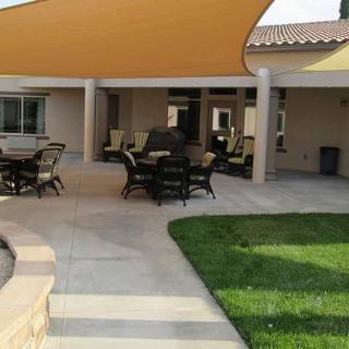 A cozy backyard patio with outdoor seating and a shade sail.