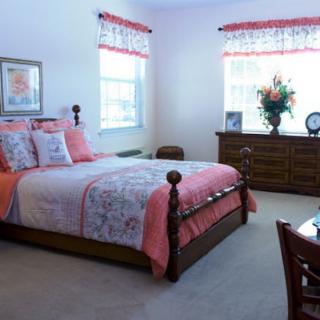A cozy bedroom with a wooden bed, dresser, and floral decor.