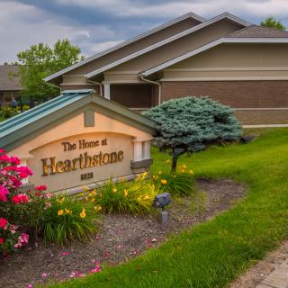A well-maintained building with colorful flowers and a sign reading 'The House at Hearthstone'.