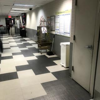 A view of a dimly lit hallway featuring tiled flooring and a closed door.