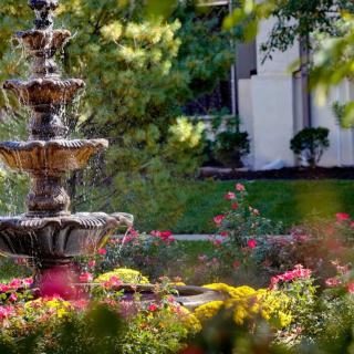 A beautiful garden with a multi-tiered fountain surrounded by vibrant flowers.