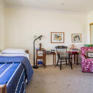A cozy bedroom with a bed, desk, chair, and vibrant armchair.