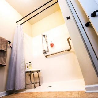 An accessible bathroom with a shower featuring grab bars and a bench.