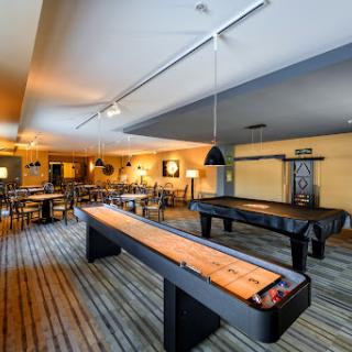 A spacious game room featuring shuffleboard tables and a cozy dining area.