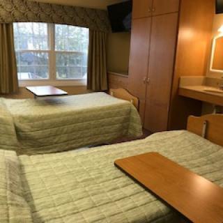 A cozy bedroom with two single beds and a window view.