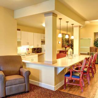 A modern open-concept kitchen and living area featuring a long counter with bar stools, warm lighting, and cozy seating.