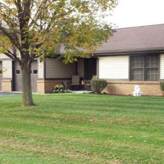 A suburban house with a well-kept lawn and a tree in the front yard.