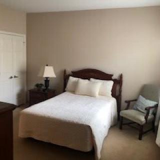 A cozy bedroom with a bed, nightstand, and chair.