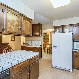 A cozy kitchen with wooden cabinets, a tiled countertop, and modern appliances.