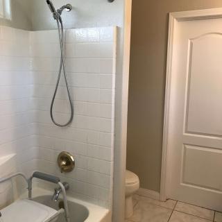 A bathroom with a shower and bathtub combination, tiled walls, and a white door.