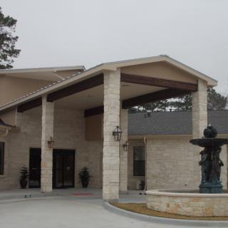 A stone building entrance with a fountain in front.