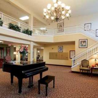 A spacious lobby with a grand piano, elegant chandelier, and a staircase.