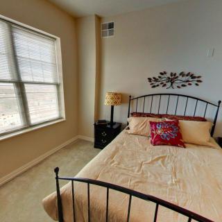 A bright bedroom with a decorative bed and window letting in sunlight.