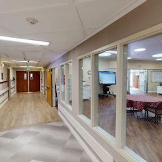 A well-lit corridor in a healthcare facility featuring glass walls and a modern design.