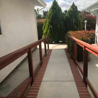 An outdoor ramp with wooden handrails leading through a garden area.