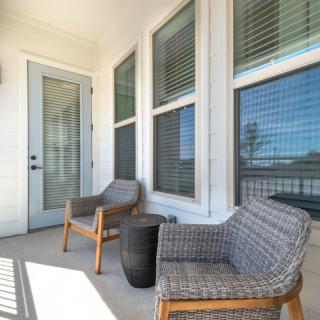 A cozy patio with wicker chairs and a small table, bathed in sunlight.