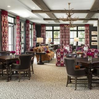 A stylish dining room with patterned curtains, elegant lighting, and comfortable seating arrangements.
