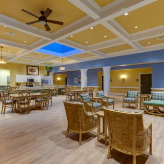 A spacious and well-lit lounge area with comfortable seating and a ceiling fan.