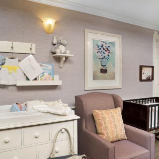 A cozy nursery featuring a crib, changing table, and a comfortable armchair.