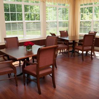 A bright and inviting dining area with wooden floors, surrounded by large windows.