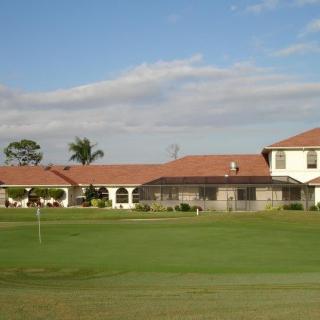 A scenic view of a golf course with a clubhouse in the background.