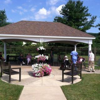 A gazebo in a garden setting with people enjoying the sunny day.