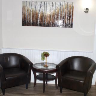A cozy seating area with two leather chairs, a small round table, and artwork on the wall.