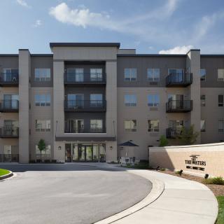 A modern apartment building with multiple balconies and a curved driveway.