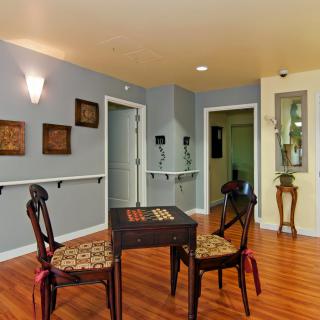 A cozy room with a small table and two chairs, featuring wooden flooring and elegant wall decorations.