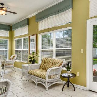 A bright and inviting sunroom with wicker furniture and large windows allowing natural light to flood the space.