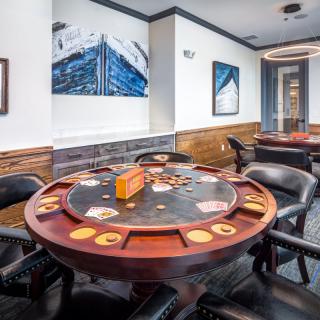 A well-appointed game room featuring a poker table surrounded by chairs, adorned with artwork on the walls.