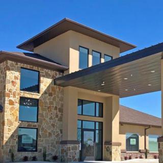 A modern building with a stone facade and large windows under a clear blue sky.