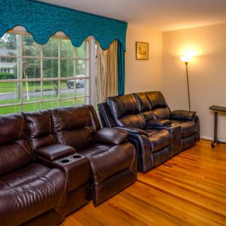 A cozy living room with a brown leather recliner sofa and a standing lamp by the window.